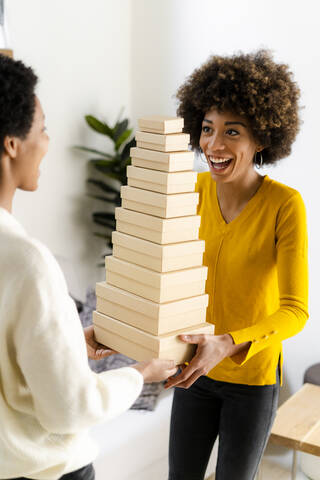 Portrait of laughing young woman balancing stack of boxes stock photo