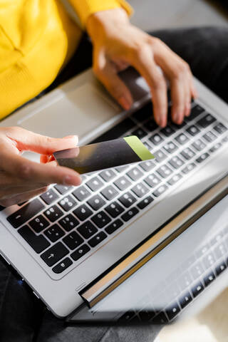 Eine Frau hält eine Kreditkarte in der Hand und benutzt einen Laptop, lizenzfreies Stockfoto