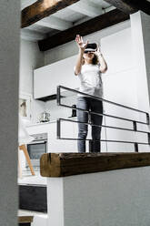 Young woman using Virtual Reality Glasses at home - GIOF08335