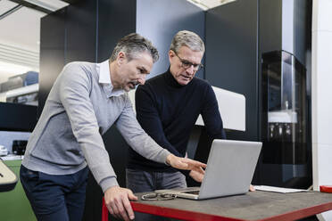 Männliche Vorgesetzte diskutieren in einer Fabrik über einen Laptop - DIGF12619