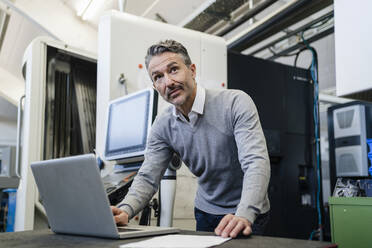 Nachdenklicher männlicher Vorgesetzter mit Laptop in der Industrie - DIGF12625