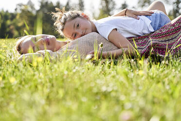 Cute girl lying on mother while relaxing during sunny day - AUF00537