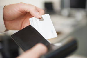 Ein Mann hält eine Brieftasche und eine leere weiße Kreditkarte in den Händen - DIGF12668