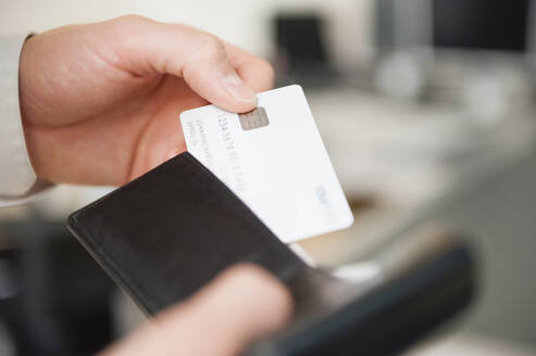 Hands of man holding wallet and blank white credit card - DIGF12668