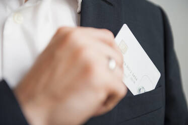 Businessman removing credit card from suit pocket - DIGF12669