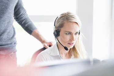 Female customer service representative wearing headset while using computer in office - DIGF12695