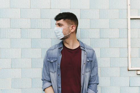 Man with protective mask in front of blue tiled wall - AGGF00067