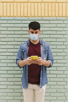 Man with protective mask using cell phone outdoors - AGGF00068