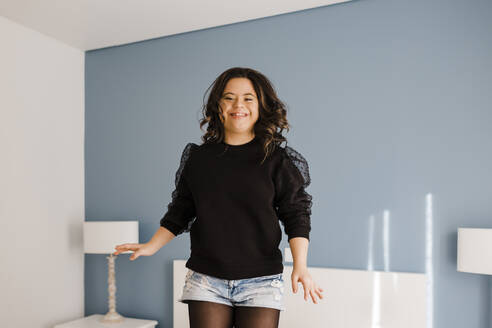 Glückliche junge Frau mit Down-Syndrom tanzt im Schlafzimmer zu Hause - DCRF00216