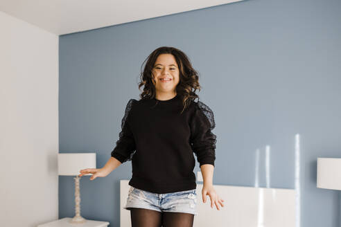 Happy young woman with down syndrome dancing in bedroom at home - DCRF00216