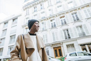 Glückliche junge Frau vor weißem Gebäude in der Stadt, Paris, Frankreich - KIJF03047