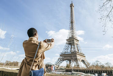 Frau fotografiert den Eiffelturm mit ihrem Smartphone gegen den Himmel, Paris, Frankreich - KIJF03062