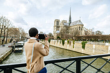 Frau fotografiert Notre Dame de Paris durch DSLR-Kamera gegen den Himmel, Paris, Frankreich - KIJF03065