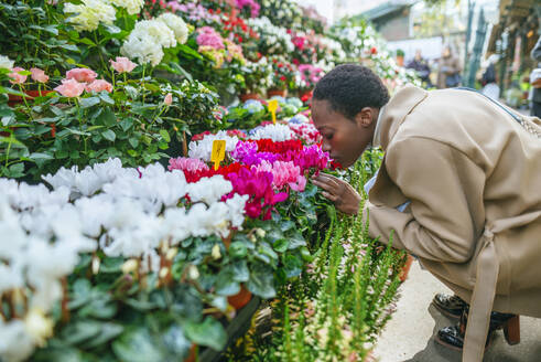 Junge Frau riecht an Blumen auf einem Markt in Paris, Frankreich - KIJF03067