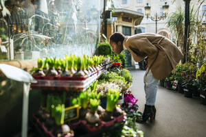 Frau riecht an Blumen auf einem Markt in Paris, Frankreich - KIJF03068