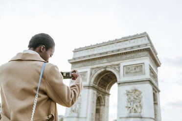 Junge Frau fotografiert Arc de Triomphe gegen den Himmel, Paris, Frankreich - KIJF03076