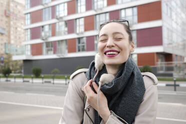 Close-up of smiling woman with white rats on scarf standing against building - EYAF01095