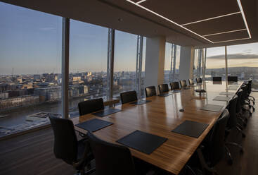 Moderner Tisch im Konferenzraum eines Hochhauses mit Blick auf die Stadt - CAIF27755