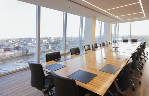 Langer Konferenztisch in einem modernen Hochhausbüro mit Blick auf die Stadt - CAIF27775