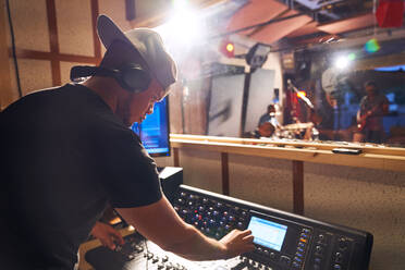 Man working at sound board in music recording studio - CAIF27792