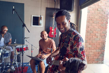 Lächelnde männliche Musiker beim Üben in einem Garagen-Aufnahmestudio - CAIF27821