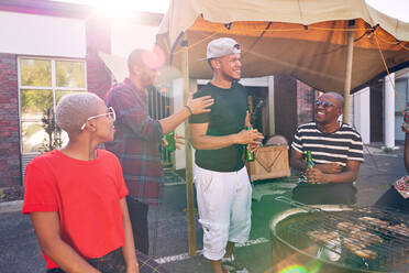 Friends hanging out and enjoying barbecue in sunny parking lot - CAIF27830