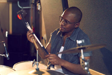 Male drummer with drum brush in recording studio - CAIF27831