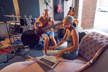 Lächelnde Musiker mit Laptop und Gitarre im Aufnahmestudio - CAIF27843