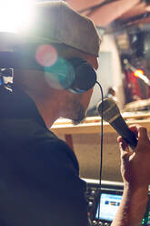 Männlicher Musikproduzent mit Mikrofon im Aufnahmestudio - CAIF27855