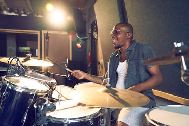 Male musician playing drums in recording studio - CAIF27864