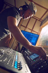 Male music producer at sound board in recording studio - CAIF27867