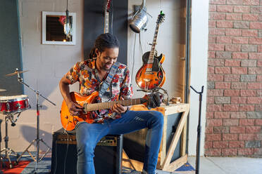 Männlicher Musiker spielt E-Gitarre in einem Aufnahmestudio in einer Garage - CAIF27870