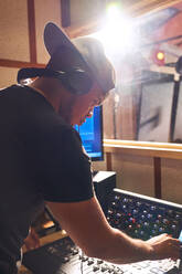 Male music producer at sound board in recording studio - CAIF27880