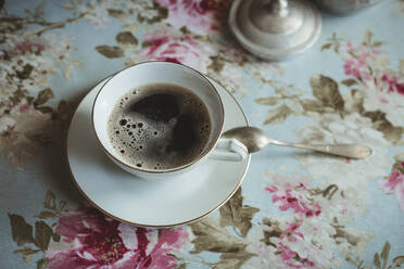 Tasse mit Kaffee auf Tisch mit Blumentischdecke - CAVF83878