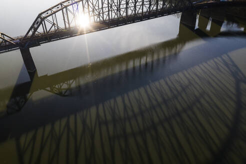 Brücke wirft bei Sonnenaufgang einen langen Schatten auf den Fluss - CAVF84026