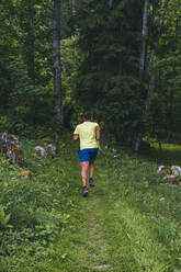 Ein junger Mann läuft durch den Wald von Chamonix, Frankreich. - CAVF84055