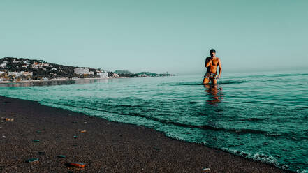 Eine Person am Strand.Mannmodell kommt aus dem Wasser.Sonnenuntergang am Strand - CAVF84082