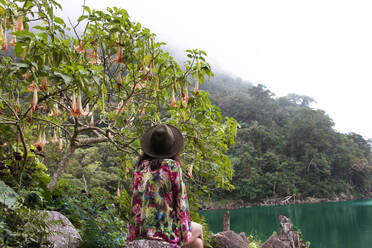 Junges Mädchen sitzt auf einem Felsen mit Blick auf eine Lagune in Dumaguete - CAVF84084