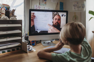 Behind view of school aged boy learning from teacher conducting class - CAVF84215