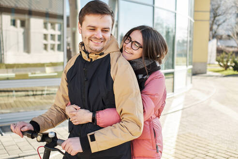 Liebevolle junge Millennials, die Spaß daran haben, auf einem Elektroroller zu laufen - CAVF84233