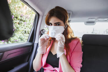 Frau trägt Maske, während sie im Auto sitzt - LJF01544