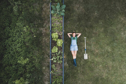 Aerial view of woman lying by raised bed on land in yard - HMEF00945