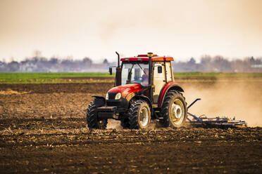 Landwirt im Traktor pflügt Bauernhof gegen den Himmel - NOF00096