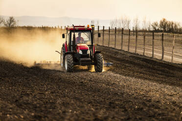 Landwirt im Traktor pflügt landwirtschaftliche Flächen gegen den Himmel - NOF00097