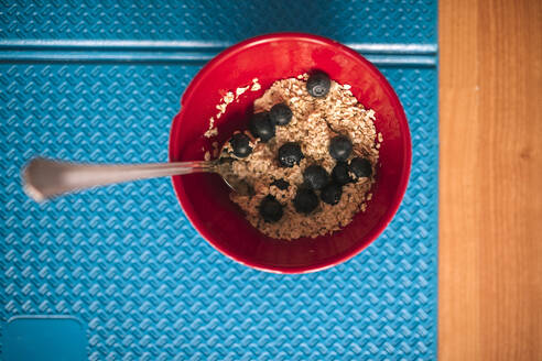 Nahaufnahme von Granola mit Blaubeeren in einer Schüssel auf einer Gymnastikmatte - GRCF00269