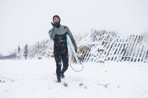 Man going surfing during winter snow - CAVF84287