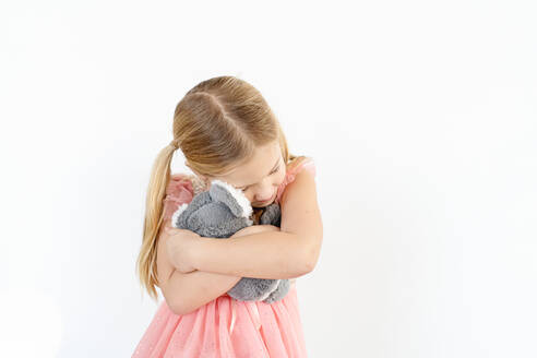 Blondes kleines Mädchen umarmt Koala-Stofftier im Haus - CAVF84392