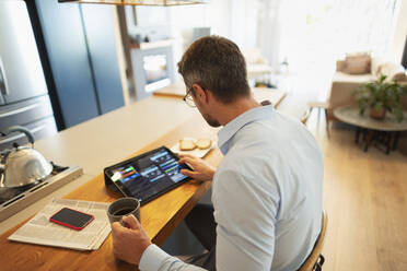 Geschäftsmann mit digitalem Tablet, der von zu Hause aus arbeitet - HOXF06273