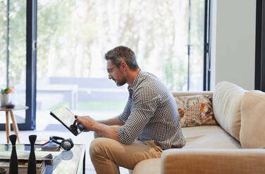 Mann mit digitalem Tablet auf dem Wohnzimmersofa - HOXF06313