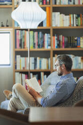 Man relaxing, reading book - HOXF06317